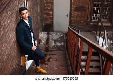 Young hipster man on stairs. A man wearing in a blue jacket , a white shirt, blue jeans and yellow boots - Shutterstock ID 375825835