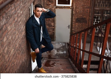Young hipster man on stairs. A man wearing in a blue jacket , a white shirt, blue jeans and yellow boots - Shutterstock ID 375825838