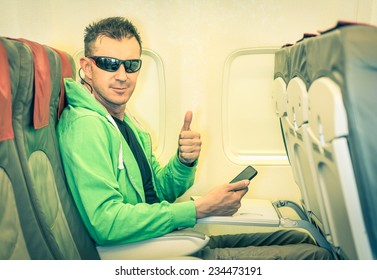 Young Hipster Man Passenger Satisfied With Thumbs Up After Boarding - Concept Of Low Coast Flight And Connection With Modern Technologies On Board - Alternative Lifestyle Traveling Around The World