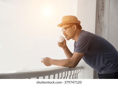 Young hipster man resting at home balcony with the sunrise