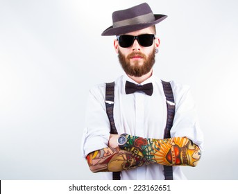 young hipster man wearing  hat , suspenders,  bow-tie and a funny tattoo-sleeve