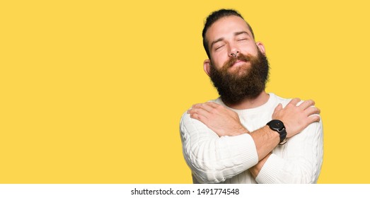 Young Hipster Man Wearing Winter Sweater Hugging Oneself Happy And Positive, Smiling Confident. Self Love And Self Care