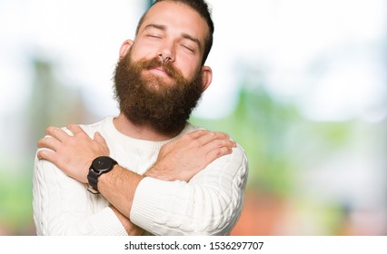 Young Hipster Man Wearing Winter Sweater Hugging Oneself Happy And Positive, Smiling Confident. Self Love And Self Care