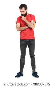 Young hipster in red t-shirt stroking beard white thinking and looking down. Full body length portrait isolated over white studio background.