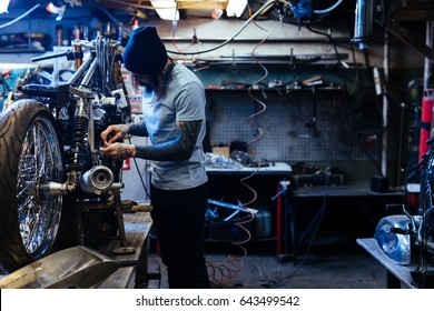 Young Hipster Repairing Custom Bike In Service Center