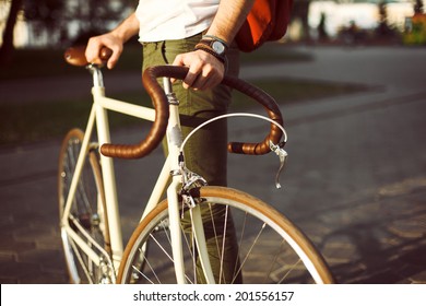 Homem de estilo jovem hipster posando com bicicleta na rua estilo esporte imagem cara bonito com mochila vermelha pronto para viagem  
