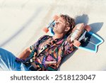 young hipster tattooed male lying with skateboard