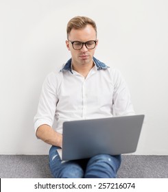 Young hipster using laptop computer while sitting on floor.
