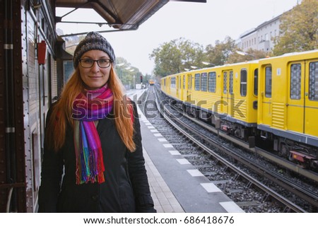 Young hipster woman in glasses and in warmclothes in train station platform