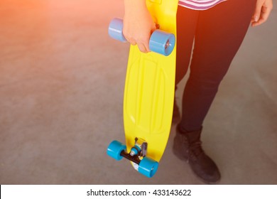 Young Hipster Woman Holding A Colorful Skateboard. Close Up Of Yellow Penny Board With Multicolored Wheels