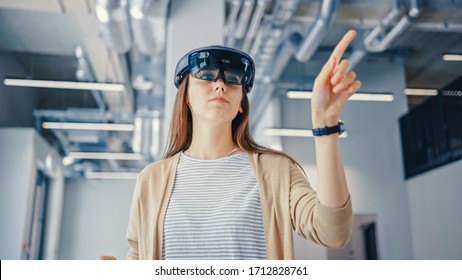 Young Hipster Woman in Holographic Augmented Reality Glasses Standing in Empty Office and Map it. Sunlight Shines Through Big Windows.