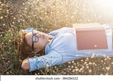 Young hipster woman lying in flower field after she tired for reading - Powered by Shutterstock