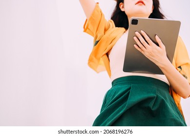 Young Hipster Woman On Orange Summer Cardigan Using Smart Digital Tablet Pc To Surf And Browse Internet, Female Holding Tablet For Work, Communication And Business. Modern Technology And Social Media