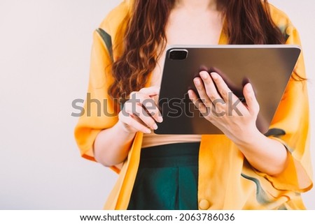 Young hipster woman on orange summer cardigan using smart digital tablet pc to surf and browse internet, Female holding tablet for work, communication and business. Modern technology and Social Media