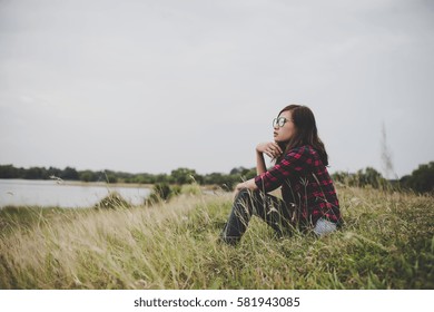 Young hipster woman sitting on grass near the lake relaxing enjoy with fresh air.