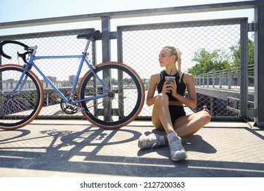 Young Hipster Woman In Sporty Shorts, With Fresh Juice Resting Near Vintage, Retro Bicycle - Cyclo Cross Bicycle On Playground Background. Blonde Female Resting After Fast Bike Riding. Summer Style