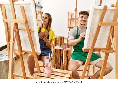 Young hispanic artist couple smiling happy drawing at art studio. - Powered by Shutterstock