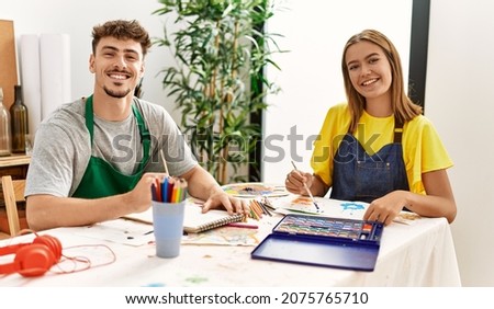 Young hispanic artist couple smiling happy drawing at art studio.