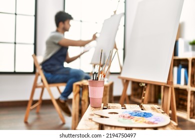 Young Hispanic Artist Man Smiling Happy Painting At Art Studio.