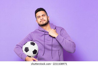 Young Hispanic Athlete Man Scared Expression And Holding A Soccer Ball