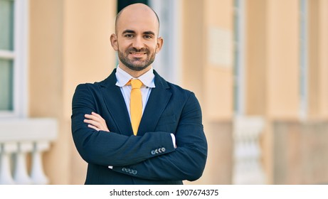 Young hispanic bald businessman with arms crossed smiling happy at the city.