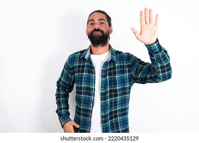 Young Hispanic Bearded Man Wearing Plaid Shirt Over White Background Waiving Saying Hello Or Goodbye Happy And Smiling, Friendly Welcome Gesture.