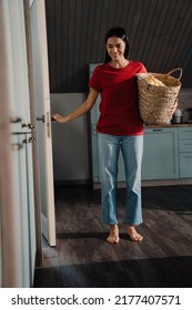 Young Hispanic Brunette Woman Holding Basket With Clothes While Doing Laundry At Home