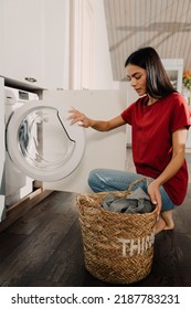 Young Hispanic Brunette Woman Putting Clothes At Washing Machine While Doing Laundry At Home