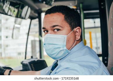 Young Hispanic Bus Driver Wears Blue Mask In Bus To Protect Himself From The Coronavirus Epidemic Is Alone In Bus. Covid 19. Protect From Corona Virus. Quarantine 2020. Stay Home.