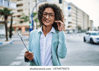 Young Hispanic Business Woman Wearing Professional Look Smiling Confident At The City Holding Worker Clipboard