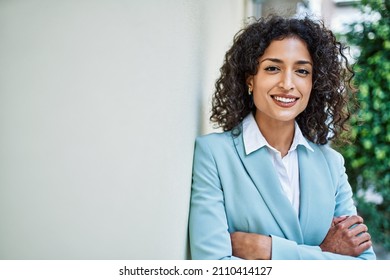 Young hispanic business woman wearing professional look smiling confident at the city leaning on the wall - Shutterstock ID 2110414127
