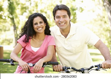 Young Hispanic Couple Cycling In Park