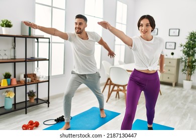 Young Hispanic Couple Doing Yoga At Home