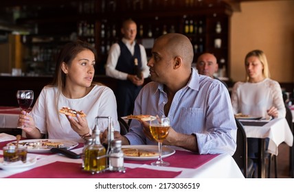 Young Hispanic Couple Enjoying Dinner With Delicious Pizza And Wine In Cozy Italian Restaurant