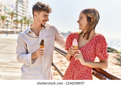 Young Hispanic Couple On Vacation Smiling Happy Eating Ice Cream At The Beach