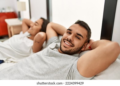 Young Hispanic Couple Relaxing With Hands On Head Lying In Bed At Home.