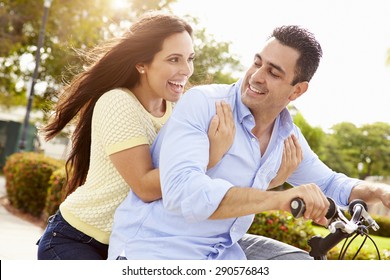 Young Hispanic Couple Riding Bikes In Park