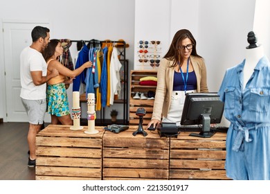 Young Hispanic Couple Shopping At Clothes Store. Shopkeeper Woman Smiling Happy Standing By Fashion Shop Counter.