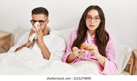 Young Hispanic Couple Sick Lying In Bed At Home.