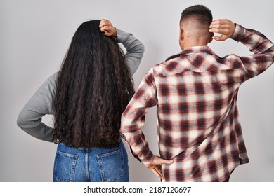 Young Hispanic Couple Standing Over White Background Backwards Thinking About Doubt With Hand On Head 