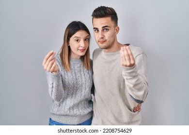 Young Hispanic Couple Standing Over White Background Doing Italian Gesture With Hand And Fingers Confident Expression 