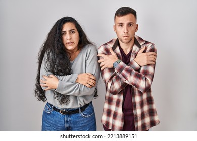 Young Hispanic Couple Standing Over White Background Shaking And Freezing For Winter Cold With Sad And Shock Expression On Face 