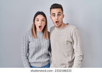 Young hispanic couple standing over white background in shock face, looking skeptical and sarcastic, surprised with open mouth  - Shutterstock ID 2332188233