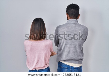 Young hispanic couple standing together standing backwards looking away with crossed arms 