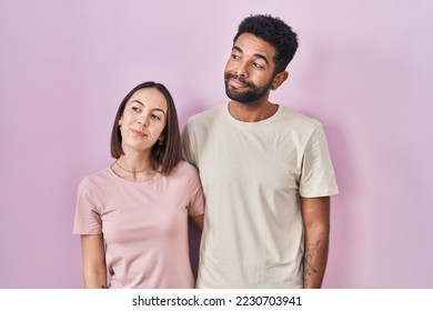 Young hispanic couple together over pink background smiling looking to the side and staring away thinking.  - Shutterstock ID 2230703941