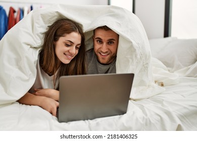 Young Hispanic Couple Watching Movie Using Laptop Lying In Bed.