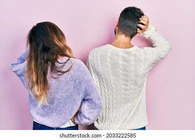 Young Hispanic Couple Wearing Casual Clothes Backwards Thinking About Doubt With Hand On Head 