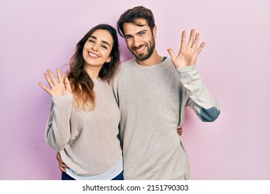 Young hispanic couple wearing casual clothes waiving saying hello happy and smiling, friendly welcome gesture 