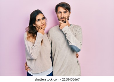 Young Hispanic Couple Wearing Casual Clothes Looking Confident At The Camera Smiling With Crossed Arms And Hand Raised On Chin. Thinking Positive. 