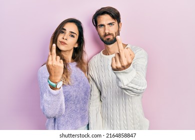 Young Hispanic Couple Wearing Casual Clothes Showing Middle Finger, Impolite And Rude Fuck Off Expression 